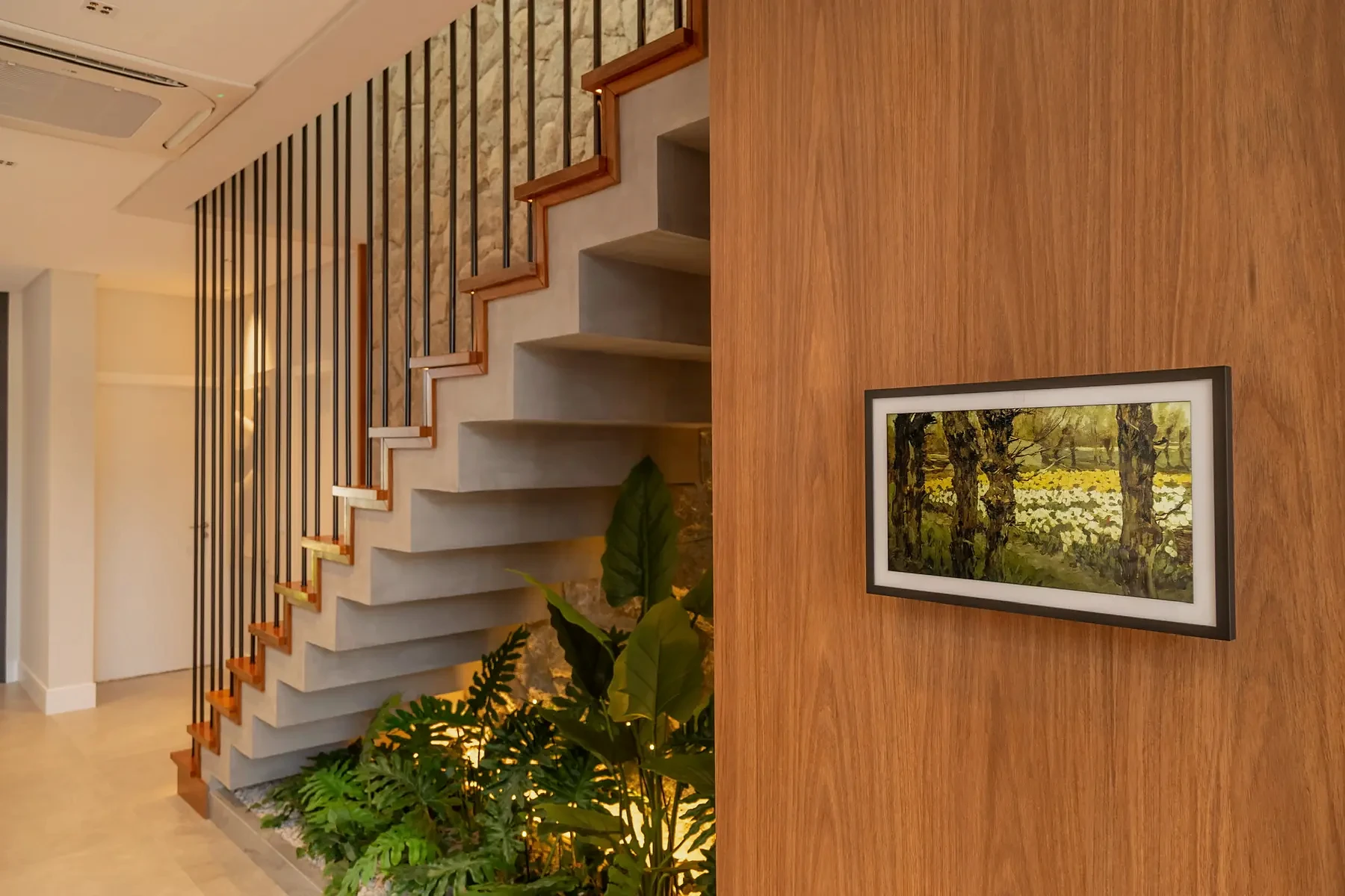 Escada iluminada, jardim interno e painel de madeira no living da Casa Pequi.
